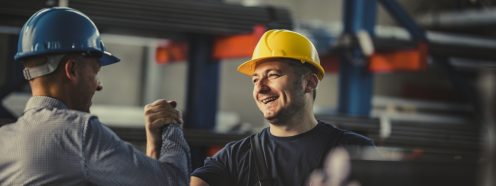 Happy metal worker greeting his manager in aluminum mill.