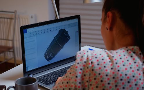 Engineer working late at night on a 3D model of industrial turbine from home. Remote freelancer studying prototype idea on personal computer showing cad software on device display