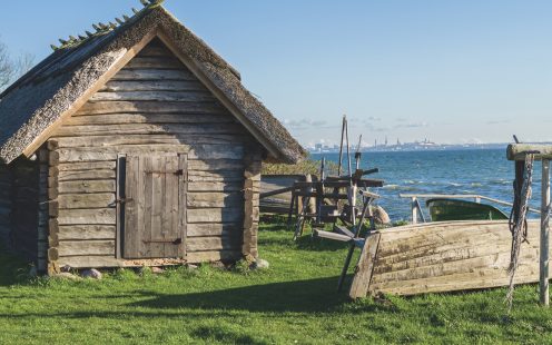 Rustic fisherman utility house and boats at sea coast, modern city on background
