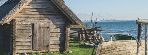Rustic fisherman utility house and boats at sea coast, modern city on background